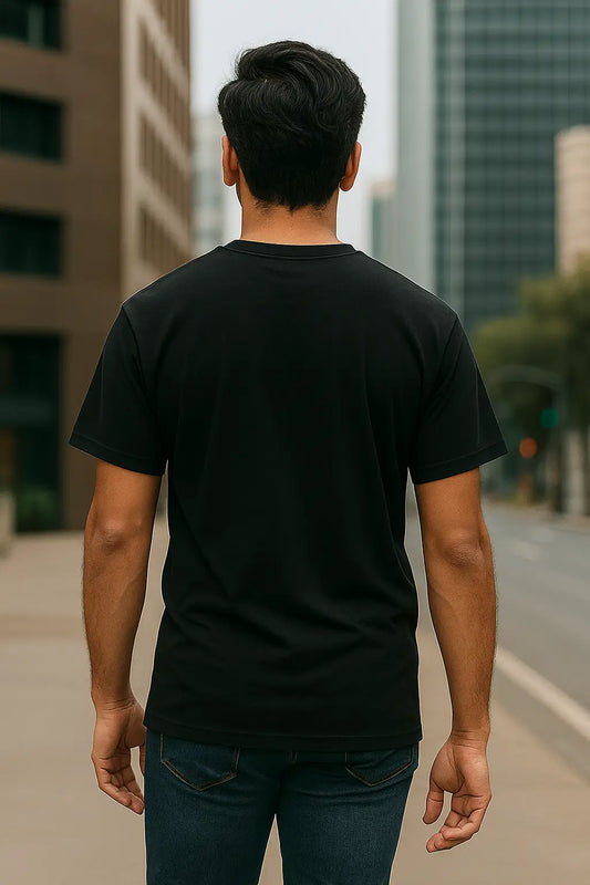 Man wearing a black t-shirt walking on a city street with tall buildings in the background