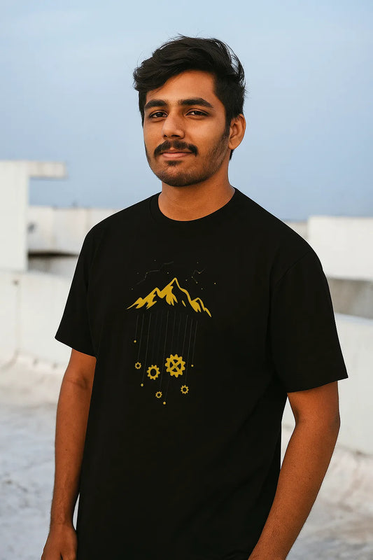 Man wearing a black t-shirt with yellow graphics against a blurred background
