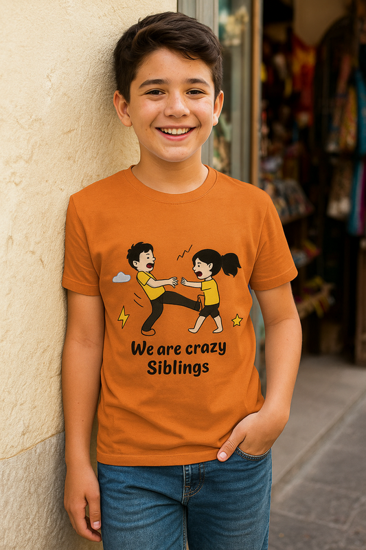Child wearing an orange t-shirt with a graphic and text, standing against a wall.